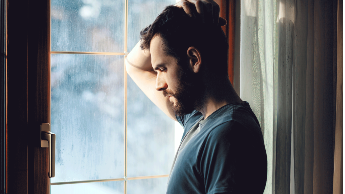 A man standing by a window thinking about the consequences of IgAN